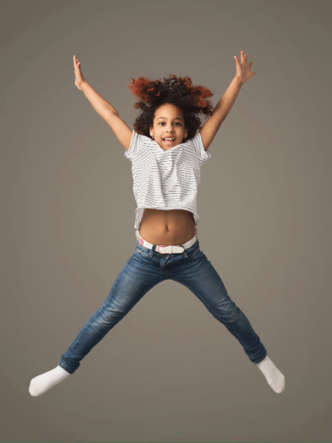 Child jumping in a star shape with arms and legs spread wide